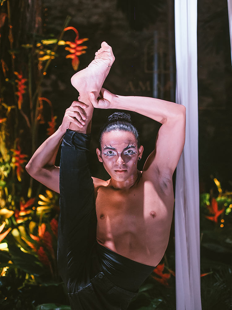 Male dancer in black satin trousers lifts right leg vertically to his ear at Amarla Boutique Hotel