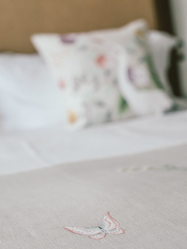 Detalle de bordado de una mariposa en la colcha de la cama en la suite Hummingbird