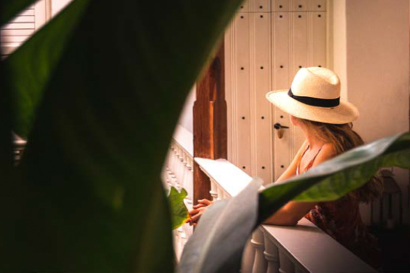 Mujer con sombrero fedora blanco leyendo un libro en el Amarla Boutique Hotel Cartagena