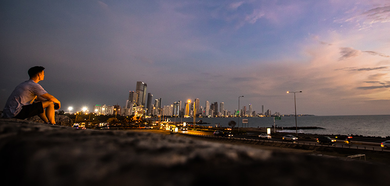 Man looking out over the sea with downtown Cartagena city lights behind